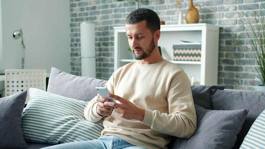 Pria bersantai memainkan ponsel di kursi sofa sebagai gambaran hiburan yang sehat