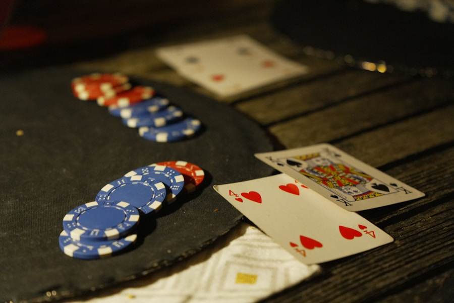 Tumpukan chip poker dan kartu remi di atas meja gelap